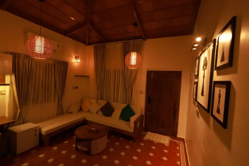 Warmly lit cottage living room with a timber ceiling and tiled floor