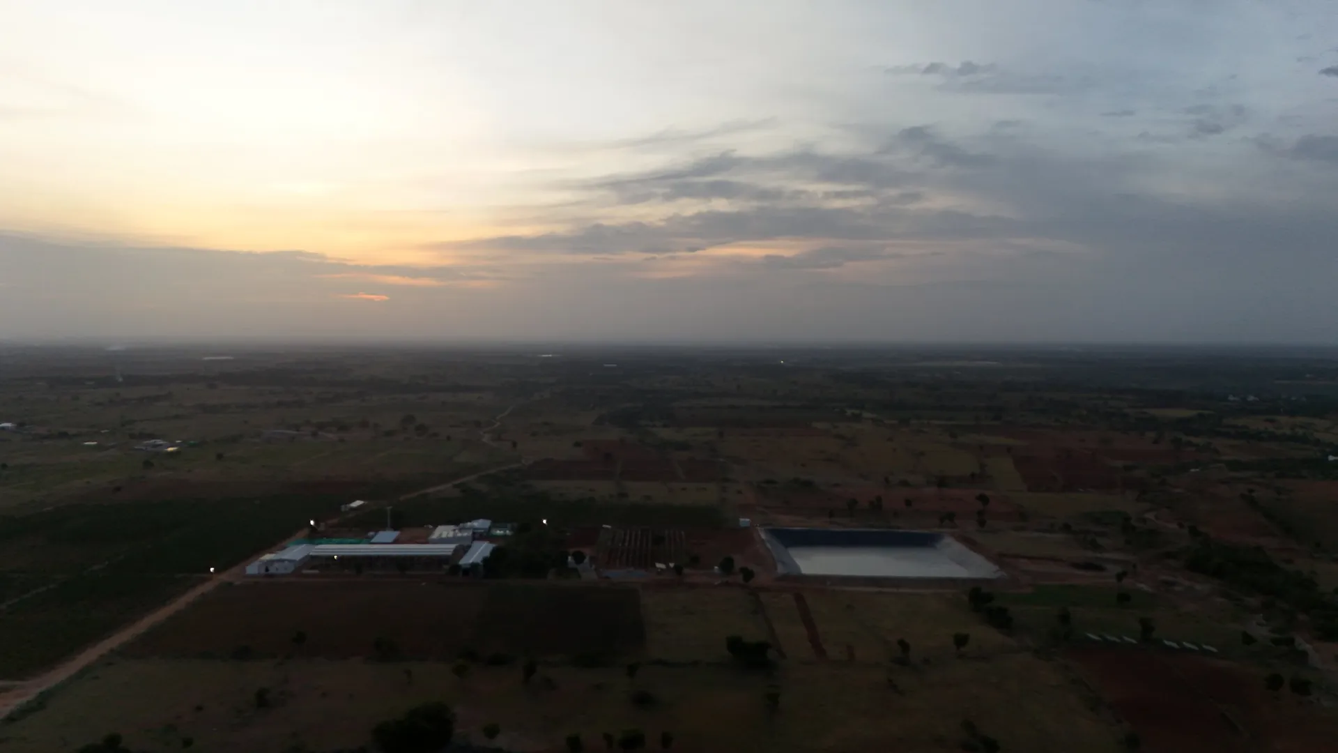 Aerial view of the GreenX campus and farm pond at dusk