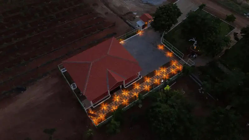 Aerial view of a farmhouse and lit garden path at dusk