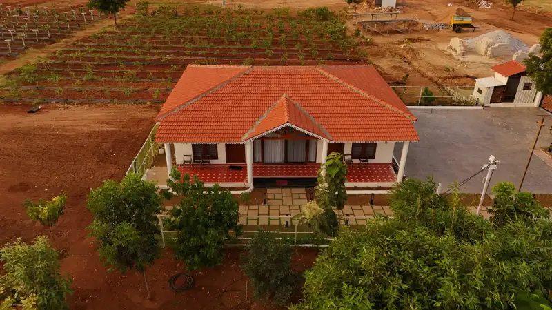 Aerial view of a tiled-roof farmhouse surrounded by planted rows